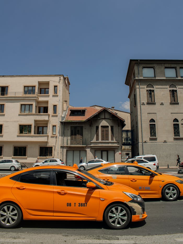 Street view of yellow taxis in front of historic buildings under clear blue sky.